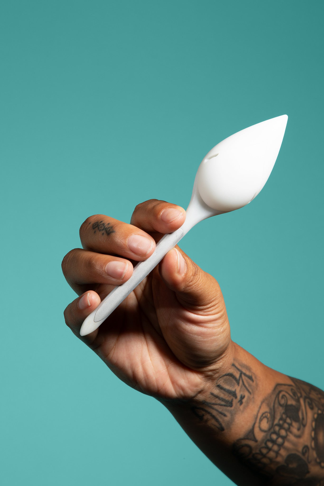 Image of A hand holding a leaflet plant sensor against a teal background.